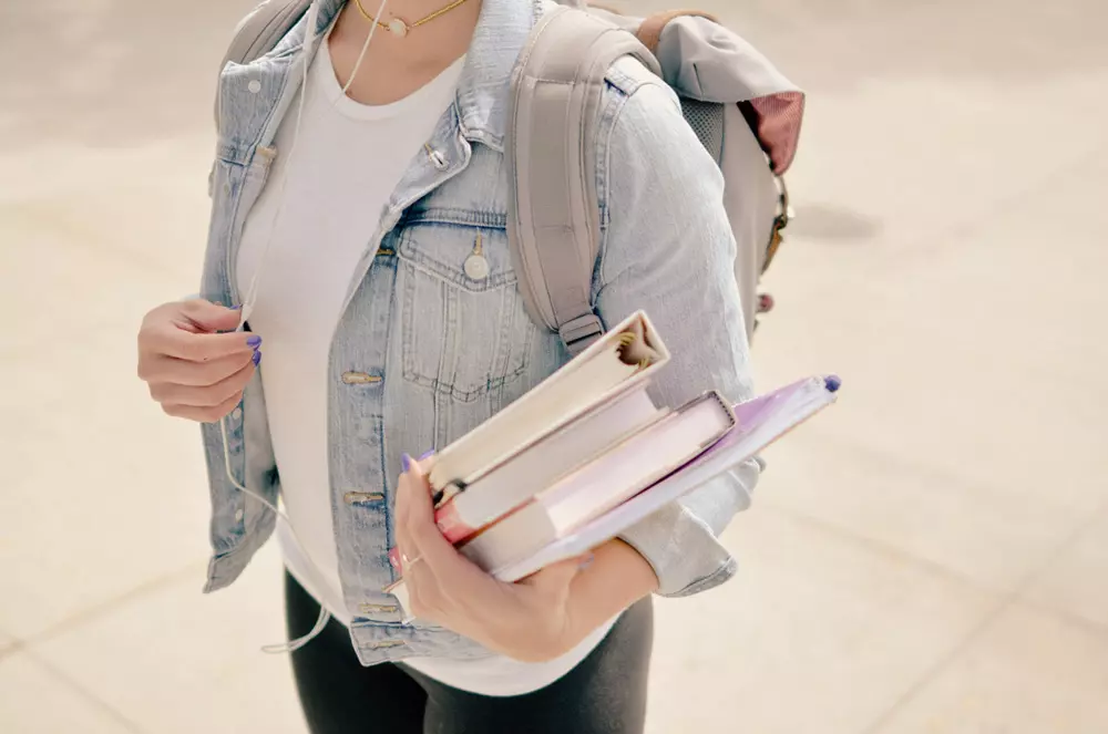studentessa con i libri in mano e lo zaino sulle spalle