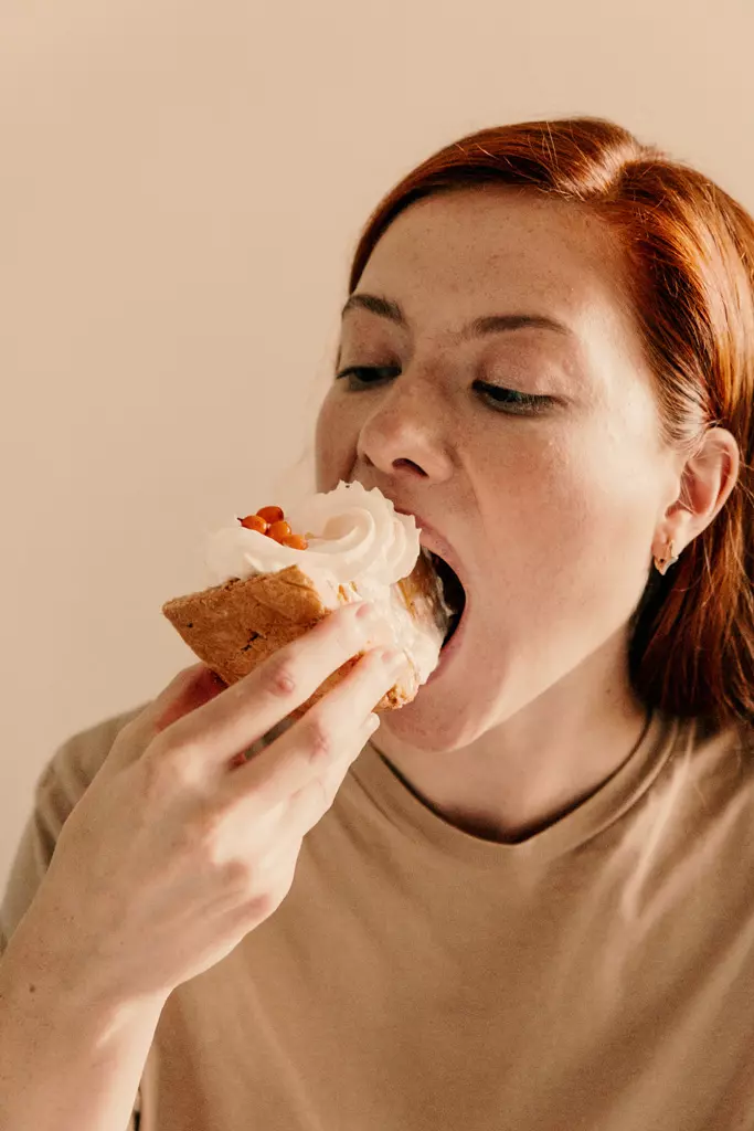 donna che si abbuffa con un dolce alla panna