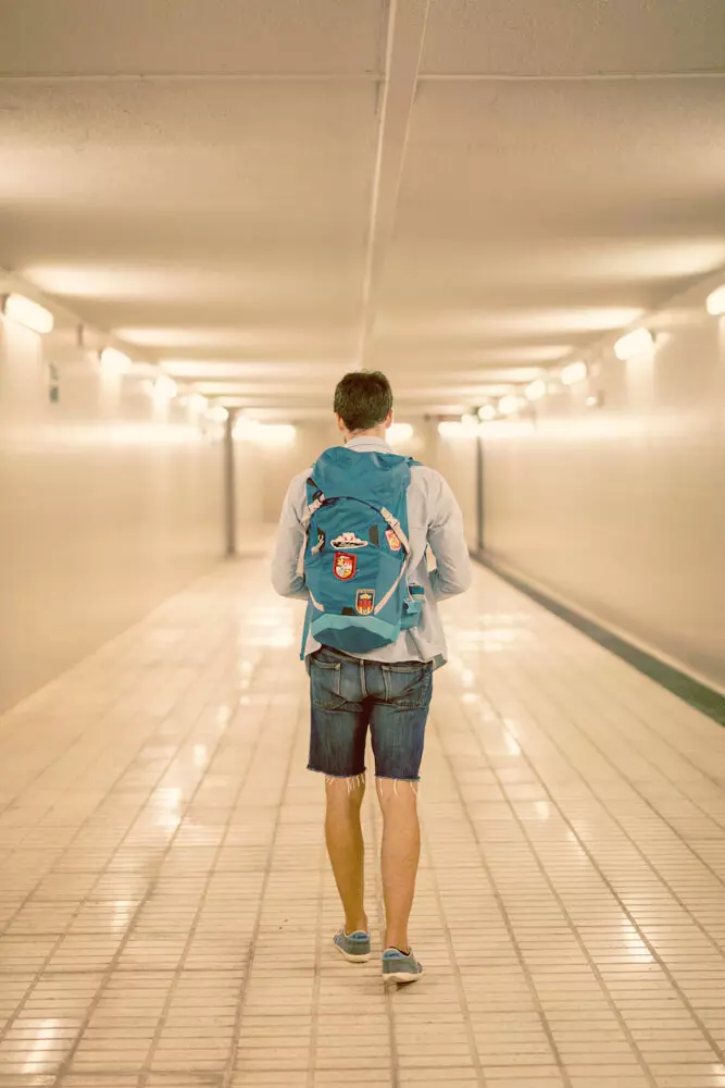ragazzo che cammina con lo zaino in spalla in un tunnel della metropolitana