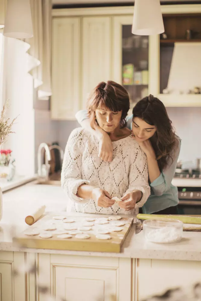 madre e figlia abbracciate in cucina mentre preparano dei dolci